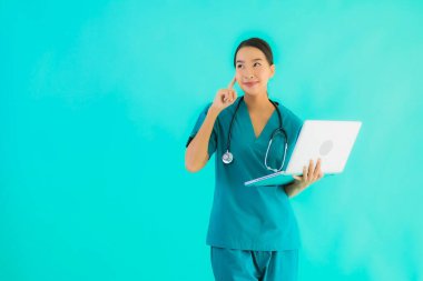 Mavi izole arka planda dizüstü bilgisayarı olan güzel Asyalı doktor kadın portresi.