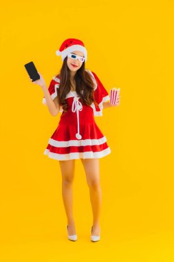 Güzel bir Asyalı kadın portresi patlamış mısır ve 3D gözlüklü noel şapkası takıyor sarı izole edilmiş arka planda film izlemeye hazır.