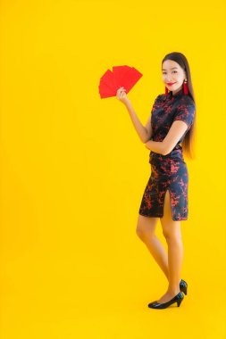Güzel bir Asyalı kadın portresi Ang Pao ile Çin elbisesi giyer ya da Çin 'in yeni yıl konsepti için sarı izole edilmiş arka planda kırmızı bir mektup.