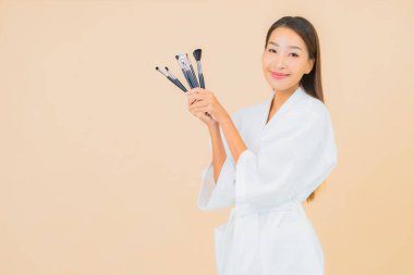 Renkli arka planda makyaj fırçası olan güzel bir Asyalı kadın portresi.