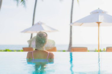 Güzel bir Asyalı kadın portresi. Tatil gezisinde deniz manzaralı açık havuz etrafında rahatça yüzebiliyor.