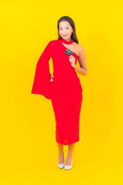 Sarı arka planda kredi kartı olan güzel bir Asyalı kadın portresi