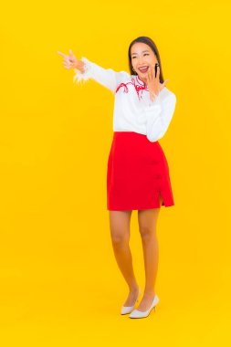 Güzel bir Asyalı kadın sarı arka planda gülümsüyor.