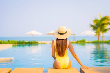 Güzel bir Asyalı kadın portresi. Rahatlayın, gülümseyin. Tatil için oteldeki yüzme havuzunun keyfini çıkarın.