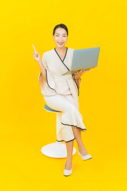 Sarı arka planda bilgisayar bilgisayarı olan güzel bir iş kadını portresi.