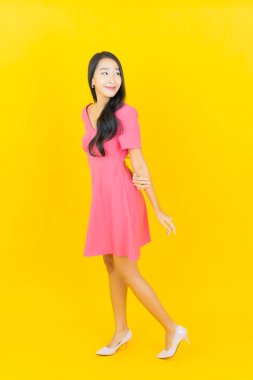 Asyalı güzel bir kadının portresi. Sarı arka planda hareketli gülümsüyor.