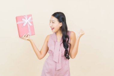 Güzel bir Asyalı kadının portresi. Arka planda kırmızı hediye kutusuyla gülümsüyor.