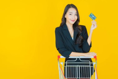 Renkli arka planda süpermarketten alınmış market sepetiyle gülümseyen güzel Asyalı kadın portresi.