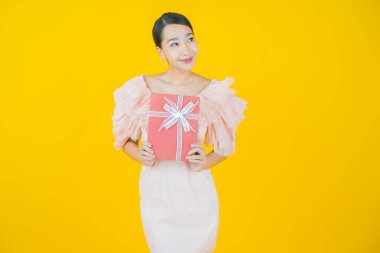 Güzel bir Asyalı kadının portresi. Arka planda kırmızı hediye kutusuyla gülümsüyor.