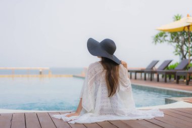 Asyalı genç bir kadının portresi mutlu bir gülümseme otel tatil beldesinde yüzme havuzunda rahatlamak