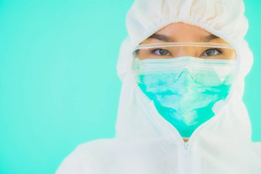 Güzel, genç Asyalı doktor kadın koronavirüsten korunmak için ppe ya da kişisel koruyucu ekipman takıyor ya da mavi izole arka planda beyaz kartı olan 19. bölgede yaşıyor.