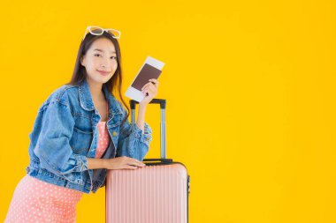 Çantalı güzel Asyalı kadın. Pasaportu ve sarı izole bir arka planda bilet.