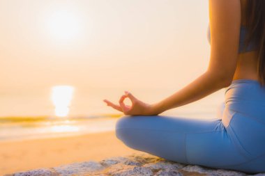 Genç Asyalı kadının portresi sağlık için gün doğumunda deniz kıyısı okyanusunda meditasyon yapıyor.