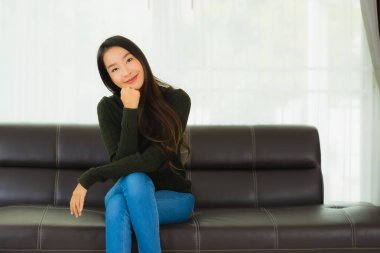 Güzel bir portre. Genç Asyalı kadın. Oturma odasındaki kanepede rahatla.