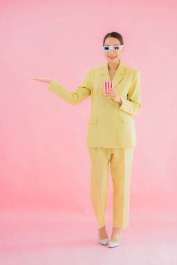 3D gözlüklü ve patlamış mısırlı güzel Asyalı kadın renkli arka planda film izlemeye hazır.