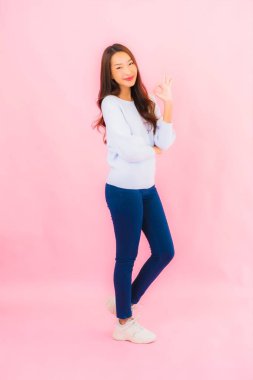 Portrait beautiful young asian woman smile with action on pink isolated background