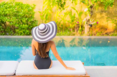 Güzel bir Asyalı kadının portresi tatil için yüzme havuzunda rahatlıyor.