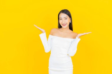 Portre güzel genç iş kadını gülümseyen ve eylem sarı arka planlı Asyalı kadın