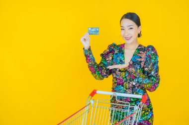 Renkli arka planda süpermarketten alınmış market sepetiyle gülümseyen güzel Asyalı kadın portresi.