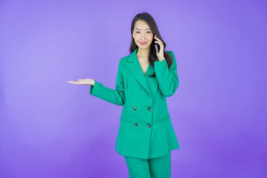 Renkli arka planda akıllı cep telefonuyla güzel Asyalı kadın gülümsemesi