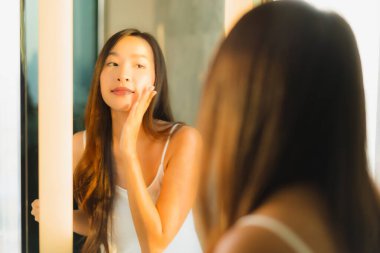 Güzel bir Asyalı kadın portresi. Banyo içinde yüzüne ve yüzüne krem sür.