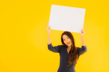 Sarı izole edilmiş arka planda boş ve boş ilan panosuyla güzel bir Asyalı kadın portresi.