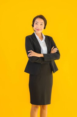 Portre güzel genç Asyalı kadın kulaklık ya da çağrı merkezi için kulaklık ya da tele pazarlama sarı izole arka planda.