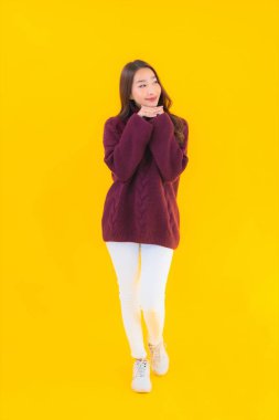 Güzel Asyalı kadın gülümsüyor. Sarı izole edilmiş arka planda başka bir eylemde mutlu.