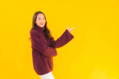 Güzel Asyalı kadın gülümsüyor. Sarı izole edilmiş arka planda başka bir eylemde mutlu.