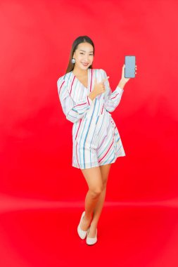 Pembe arka planda akıllı cep telefonlu güzel Asyalı kadın portresi.