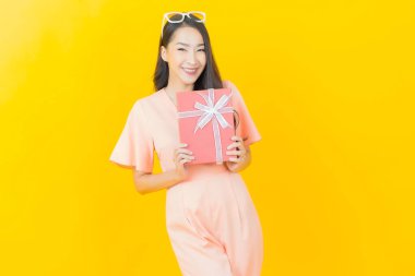 Güzel bir Asyalı kadının portresi. Arka planda kırmızı hediye kutusuyla gülümsüyor.