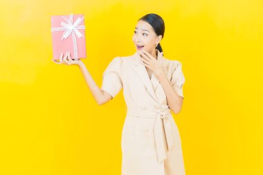 Güzel bir Asyalı kadının portresi. Arka planda kırmızı hediye kutusuyla gülümsüyor.