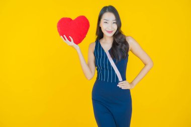 Portre güzel Asyalı genç kadın gülümsüyor kalp yastığı şeklinde renk arkaplan