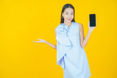 Renkli arka planda akıllı cep telefonuyla güzel Asyalı kadın gülümsemesi