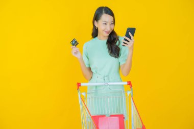 Renkli arka planda süpermarketten alınmış market sepetiyle gülümseyen güzel Asyalı kadın portresi.