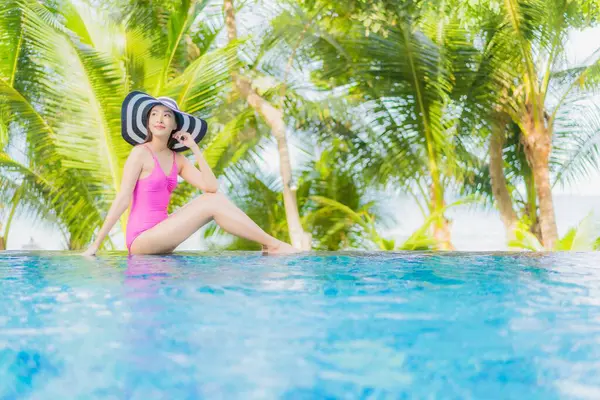 Portre güzel Asyalı kadın gülümsemesi tatil gezisinde tatil otelinde yüzme havuzunda rahatla.