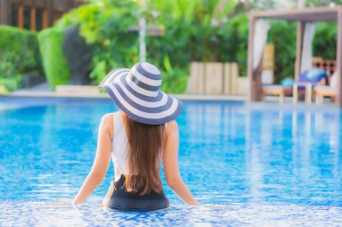 Güzel bir portre genç Asyalı mutlu bir gülümseme tatil beldesi otelinde havuzda rahatça yüzebiliyor.