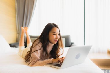 Yatak odasının iç kısmında dizüstü bilgisayar kullanan güzel Asyalı kadın portresi.