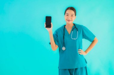 Güzel bir portre genç Asyalı doktor kadın mavi izole edilmiş arka planda akıllı cep telefonu gösteriyor.