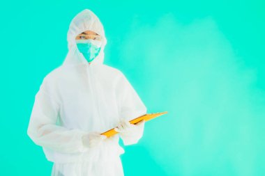 Güzel, genç Asyalı doktor kadın koronavirüsten korunmak için ppe ya da kişisel koruyucu ekipman takıyor ya da mavi izole arka planda beyaz kartı olan 19. bölgede yaşıyor.