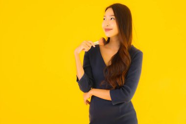 Sarı izole arkaplanda makyaj fırçası olan güzel bir Asyalı kadın portresi.