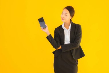 Portre güzel genç Asyalı kadın akıllı cep telefonu ve kahve fincanı ile izole edilmiş sarı arka planda