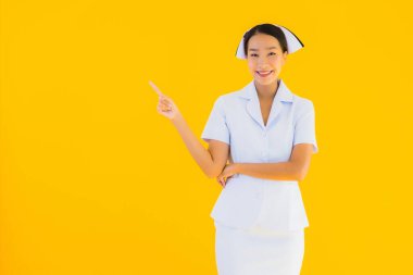 Güzel Asyalı genç Taylandlı hemşirenin portresi klinikteki ve hastanedeki hastalar için sarı izole edilmiş arka planda birçok eylem çalışmasında yer alıyor.