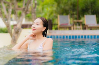 Portre güzel Asyalı kadın gülümsemesi tatil gezisinde tatil otelinde yüzme havuzunda rahatla.