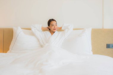 Güzel bir Asyalı kadın portresi. Rahatlayın, gülümseyin. Yatak odasında dinlenin.