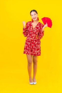 Sarı arka planda kırmızı zarfları olan güzel Asyalı kadın portresi.