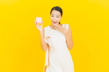 Sarı arka planda domuz kumbaralı güzel Asyalı kadın portresi.