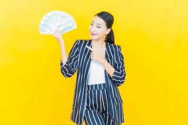 Asyalı güzel bir kadının portresi. Renkli arka planda bol para ve parayla gülümsüyor.