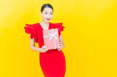 Güzel bir Asyalı kadının portresi. Arka planda kırmızı hediye kutusuyla gülümsüyor.