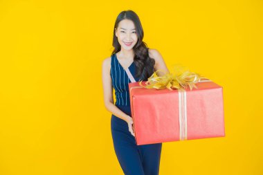 Güzel bir Asyalı kadının portresi. Arka planda kırmızı hediye kutusuyla gülümsüyor.